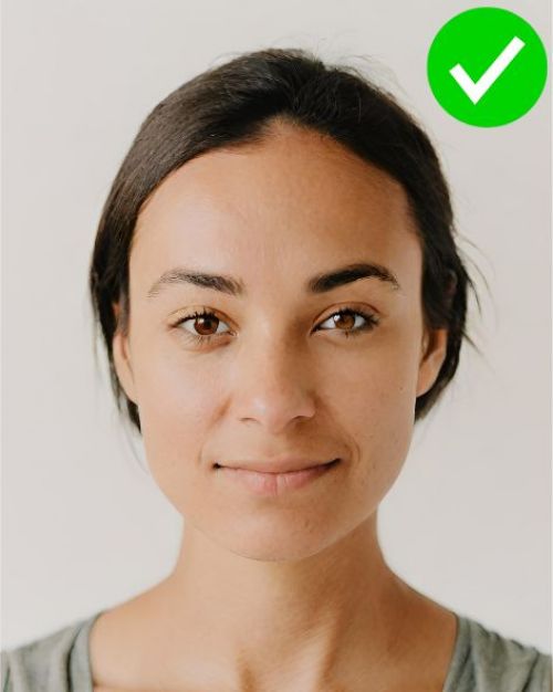 An example of an acceptable photo for an ID card with a woman centred, looking at the camera, against a light background. 