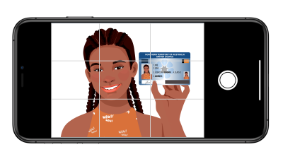 A person taking a selfie while holding their photo identification near their face