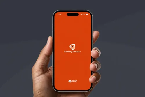A hand holding a smartphone with Territory Services written on the phone screen